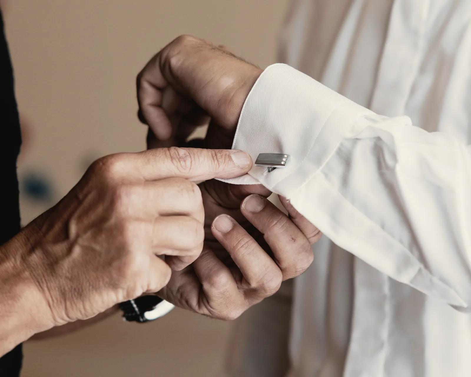 The cufflink at the cuff, held between the fingers.