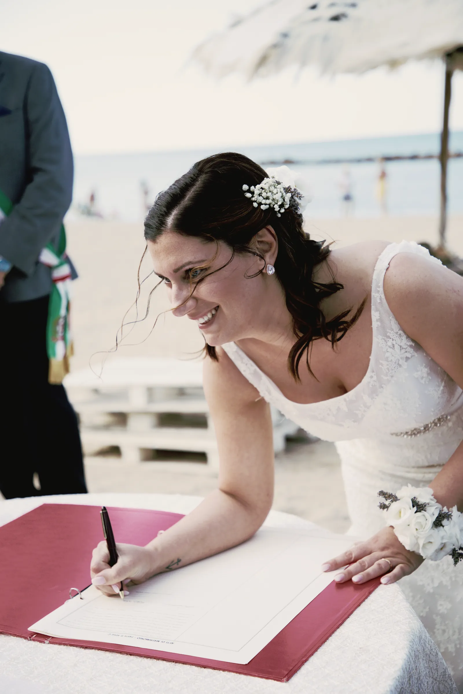 La sposa ride mentre firma il registro, piegata sul tavolo.