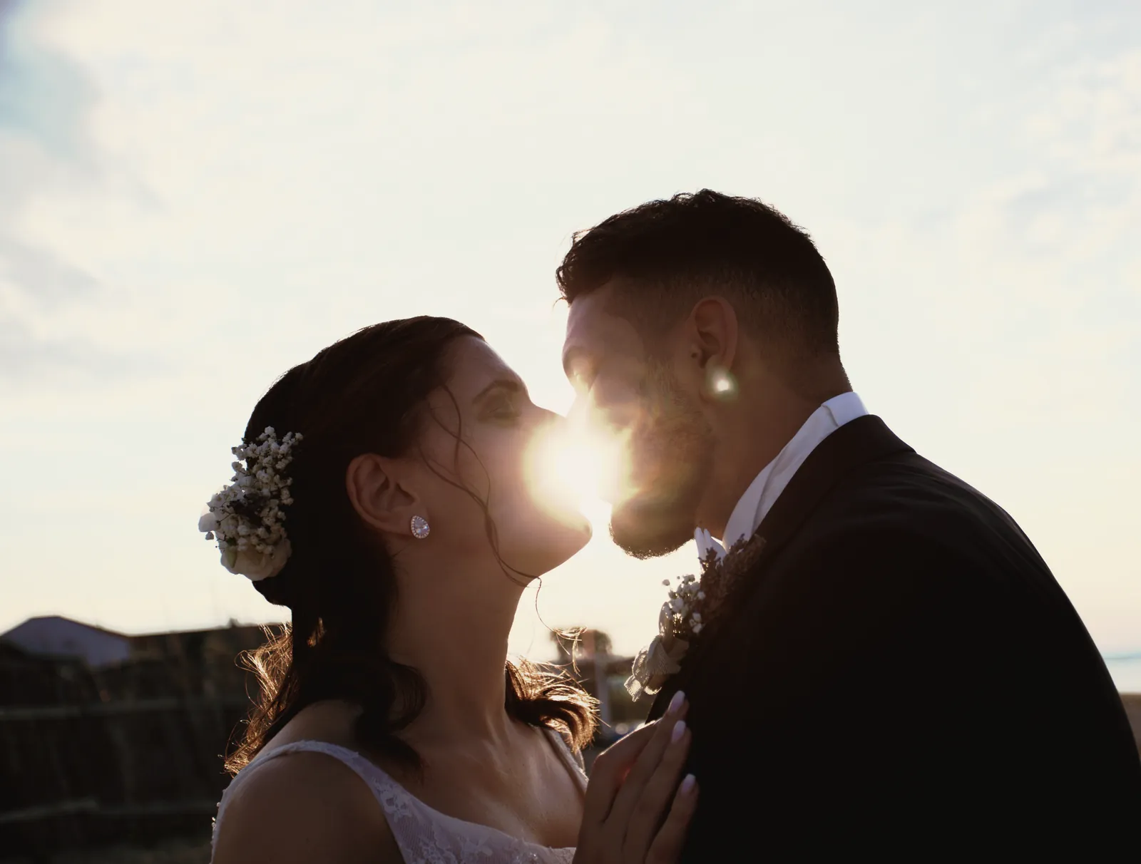 Il sole basso fra i due volti, un istante prima del bacio, le mani di lei sul petto di lui.