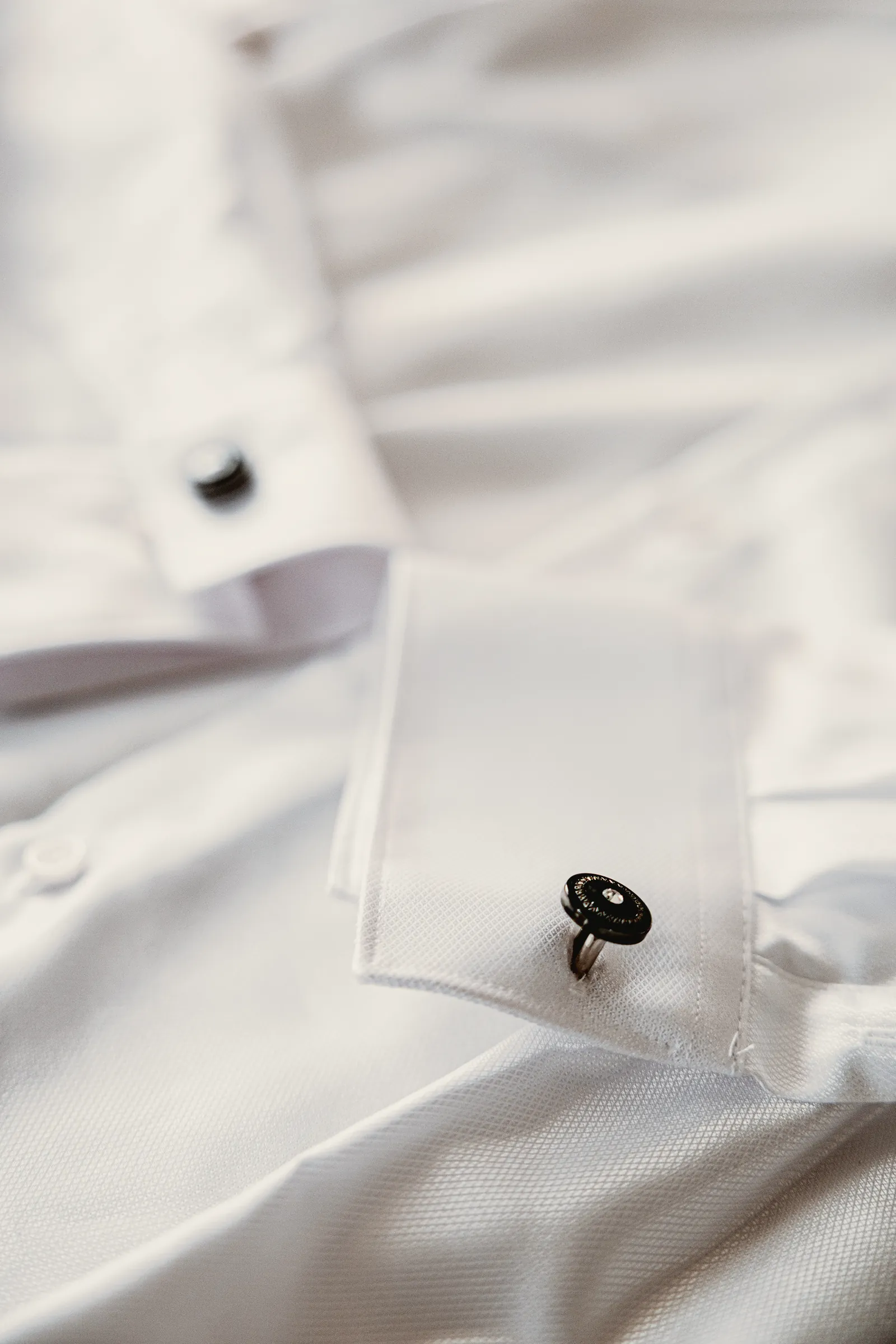 Il gemello sul polsino della camicia bianca, stesa sul letto.