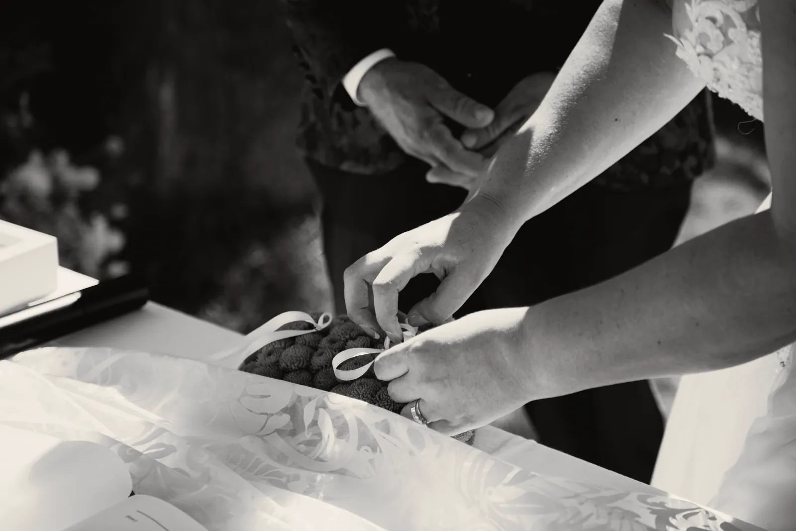 Le mani della sposa sciolgono il nastro delle fedi dal cuscino verde, sul tavolo del rito.