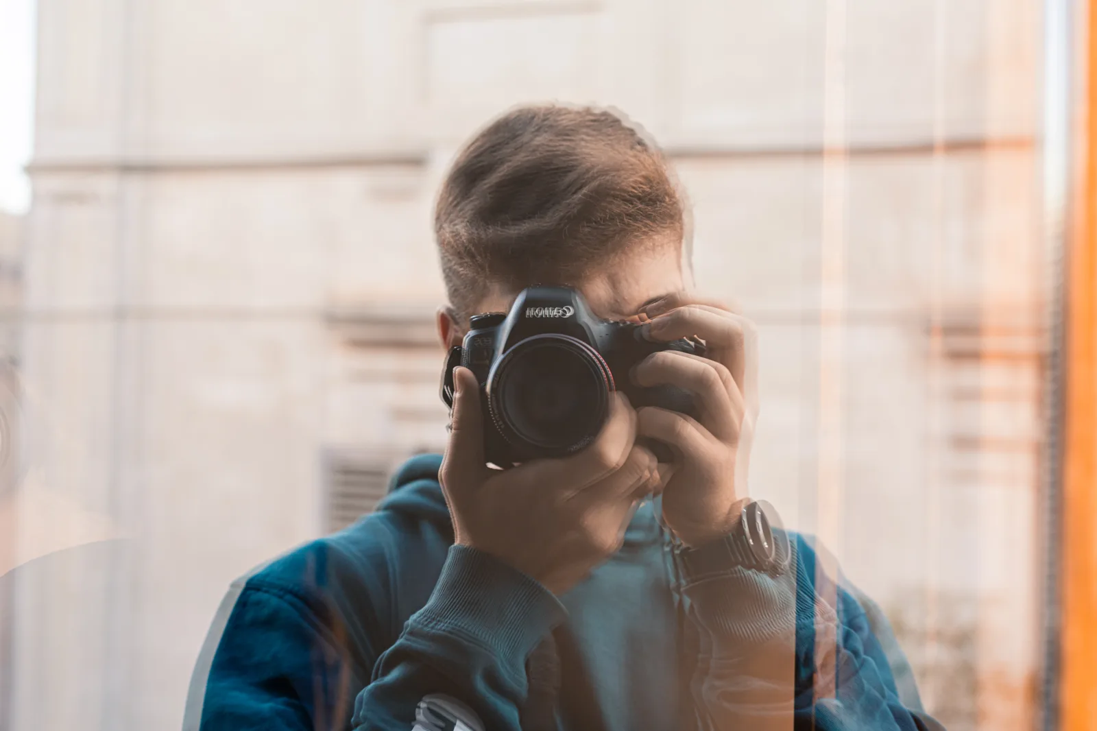 Piergiorgio Di Falco riflesso in una vetrina, la macchina fotografica davanti al viso.