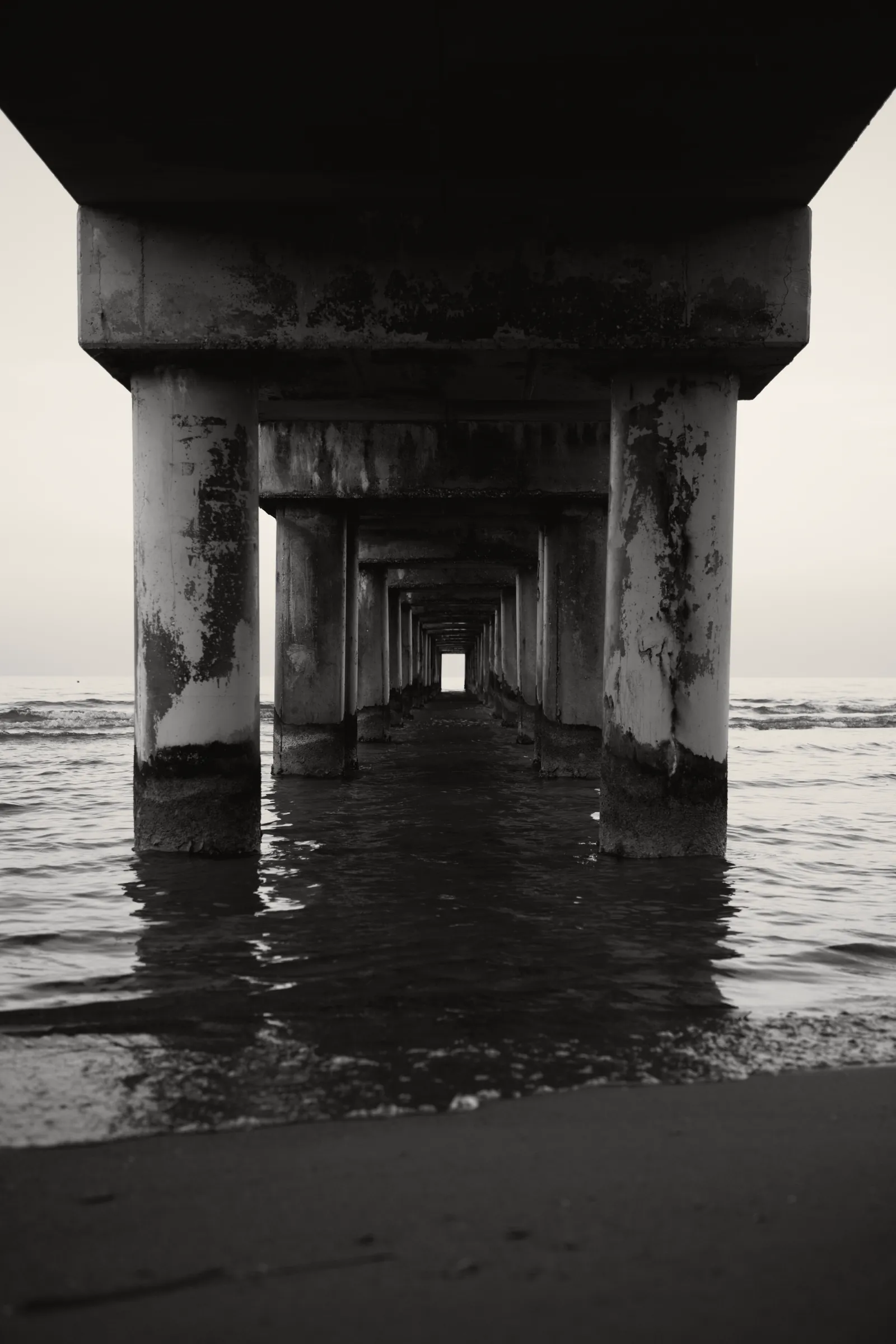Sotto il pontile: i piloni di cemento che entrano nel mare, nessuno intorno.
